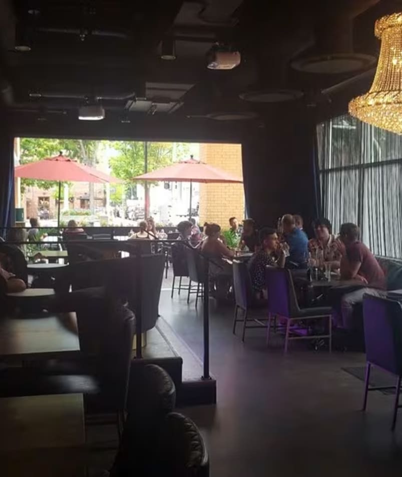 a group of people sitting at a table in a restaurant with a chandelier hanging from the ceiling