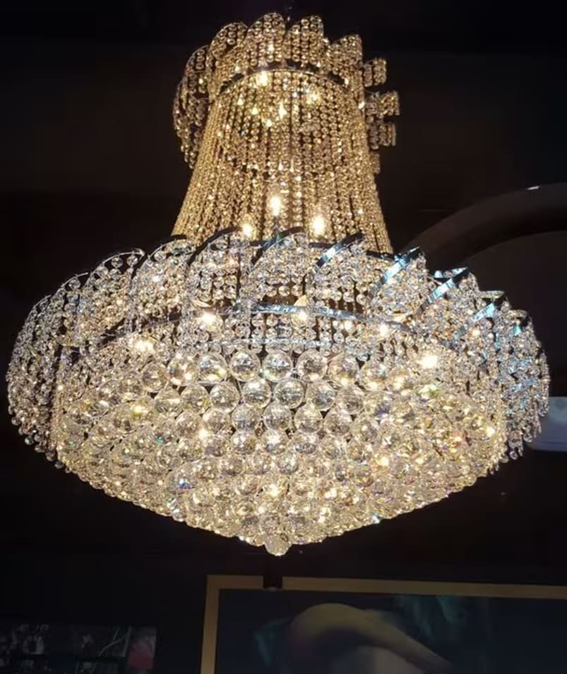 A chandelier hanging from the ceiling in a room with pictures on the wall, at Friends of Dorothy Lounge in Kelowna.