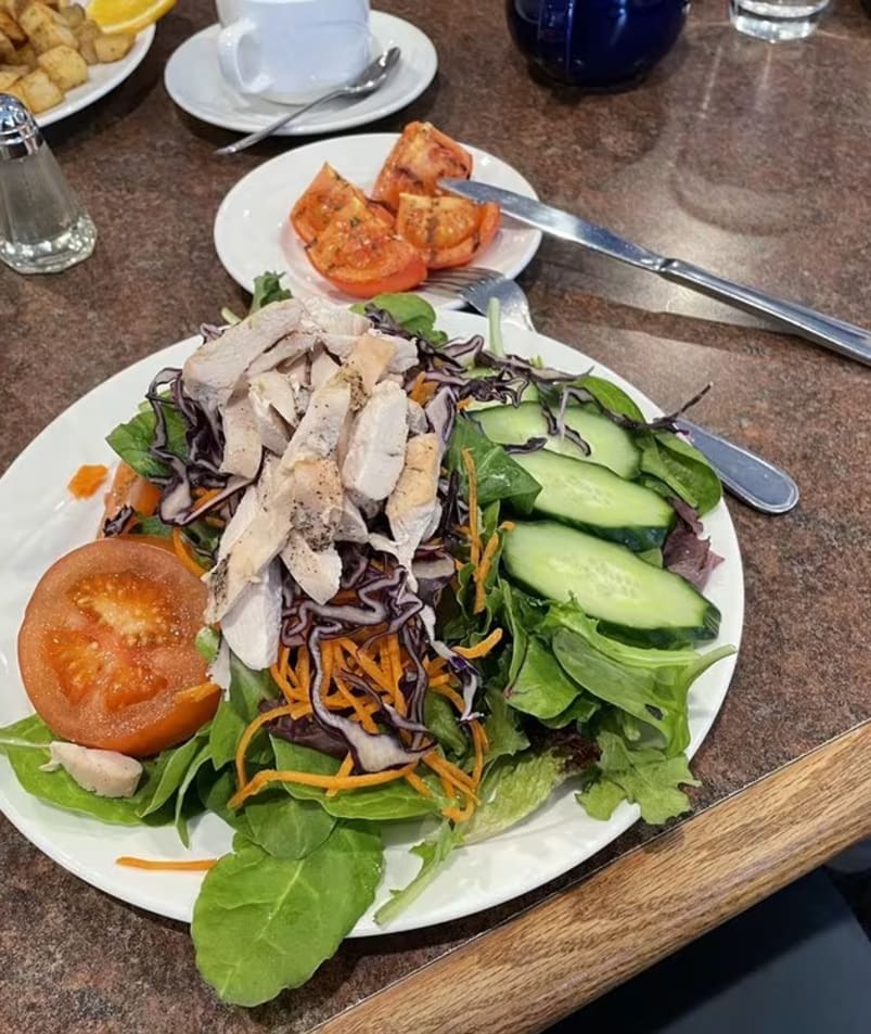 A colorful salad with sliced chicken, fresh tomatoes, cucumbers, and leafy greens served on a table at The Jammery in Lake Country.