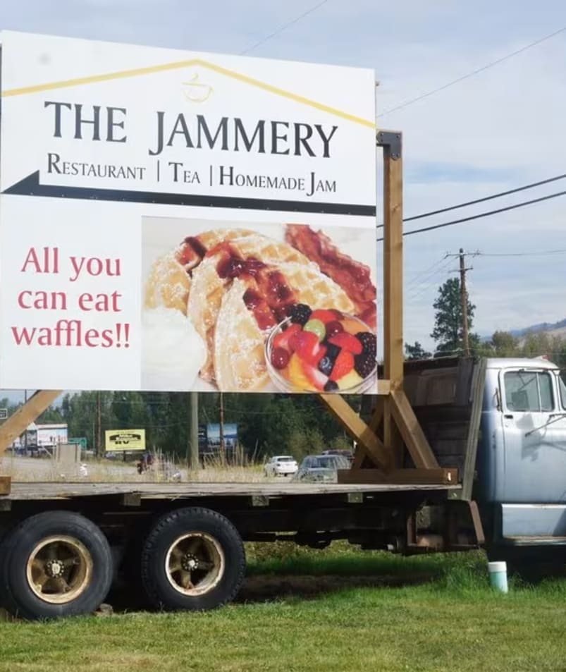 A large sign for The Jammery restaurant in Lake Country, advertising All you can eat waffles!! with an image of waffles on an old truck bed.