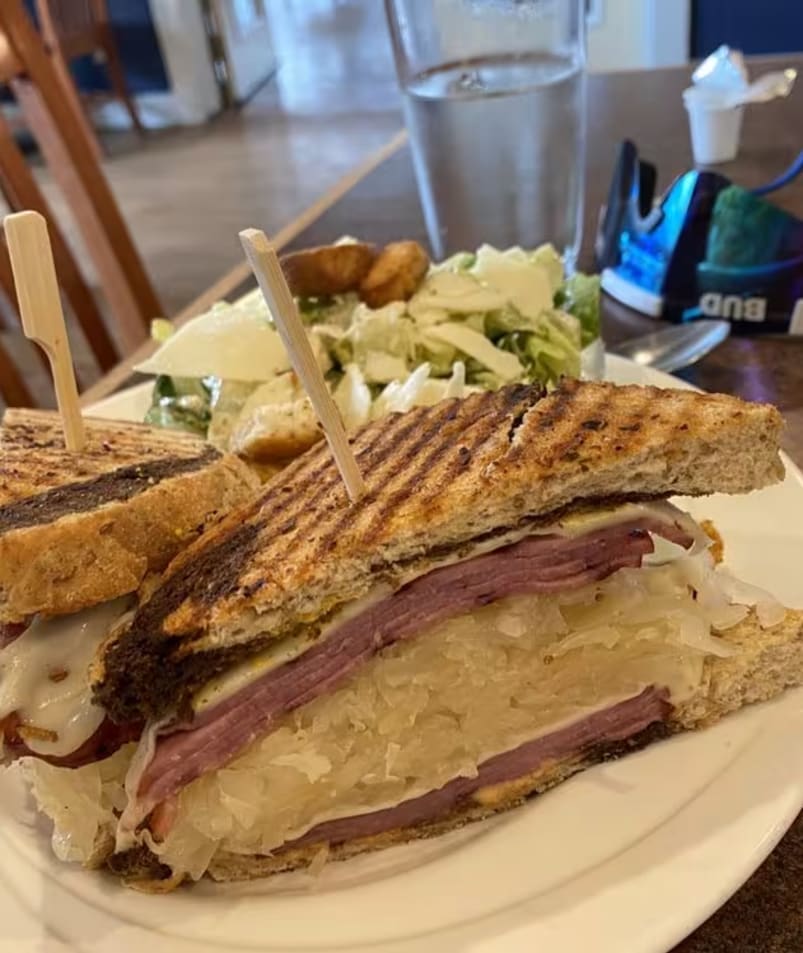 A close-up of a Reuben sandwich and a side salad on a white plate at The Jammery in Lake Country.