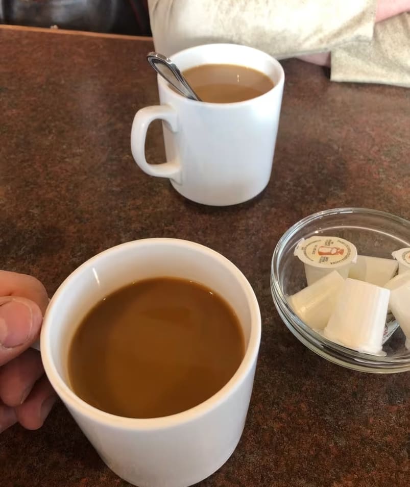 Two cups of coffee on a table at The Jammery in Lake Country with a bowl of creamers.