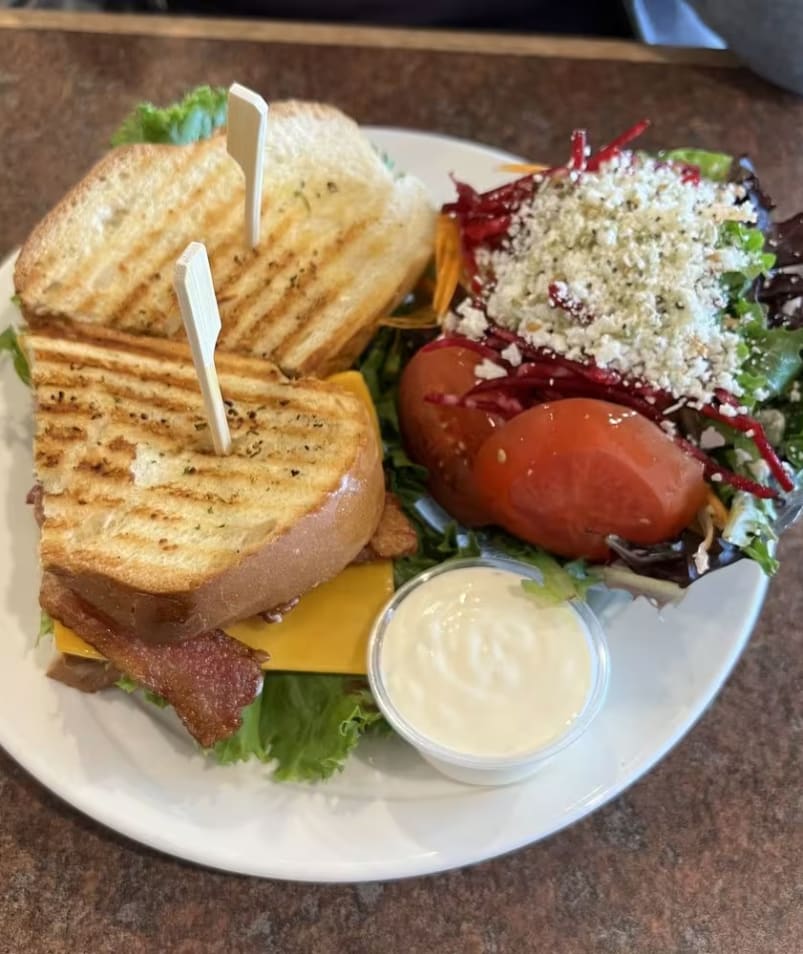 A grilled sandwich and salad with dressing on a plate at The Jammery in Lake Country.