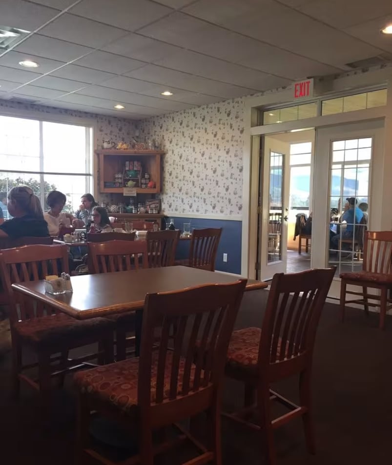 A cozy indoor dining area at The Jammery in Lake Country, featuring wooden tables and chairs, with diners enjoying their meals in the background.