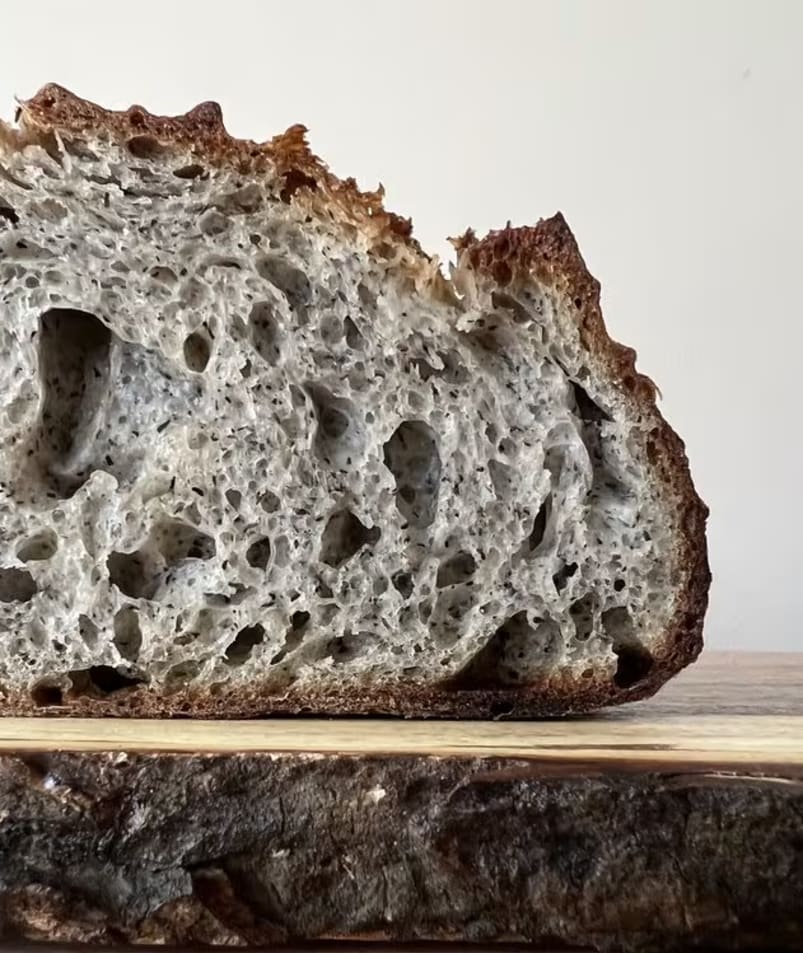 a loaf of bread sitting on top of a wooden cutting board on top of a cutting board with a slice cut out of it