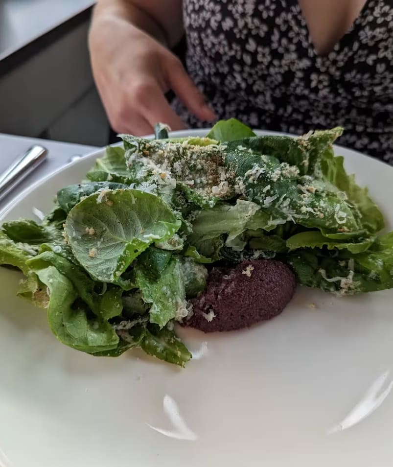A person enjoying a fresh green salad with grated cheese at Erica Jane Restaurant in Kelowna.