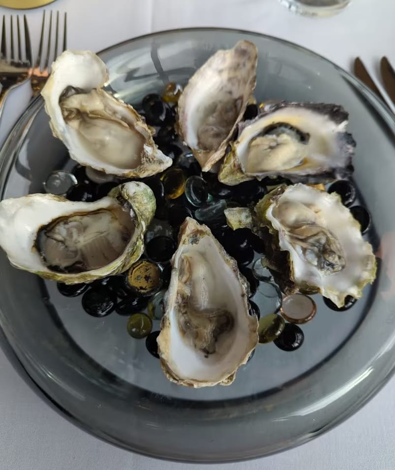 A plate of six opened oysters arranged on a glass dish at Erica Jane Restaurant in Kelowna.