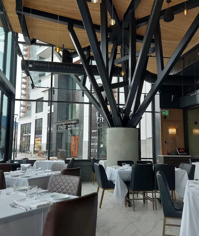 Modern interior of Erica Jane Restaurant in Kelowna with large windows, elegant furniture, and a unique ceiling structure.