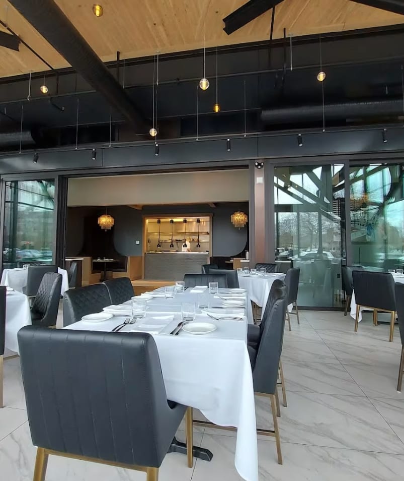 The interior of Erica Jane Restaurant in Kelowna, featuring elegantly set tables with white tablecloths, modern decor, and large windows allowing natural light.