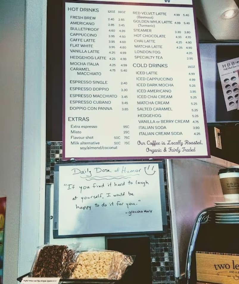 a table with a sign that says h b e f e and a bunch of pastries on it in a coffee shop in Kelowna.