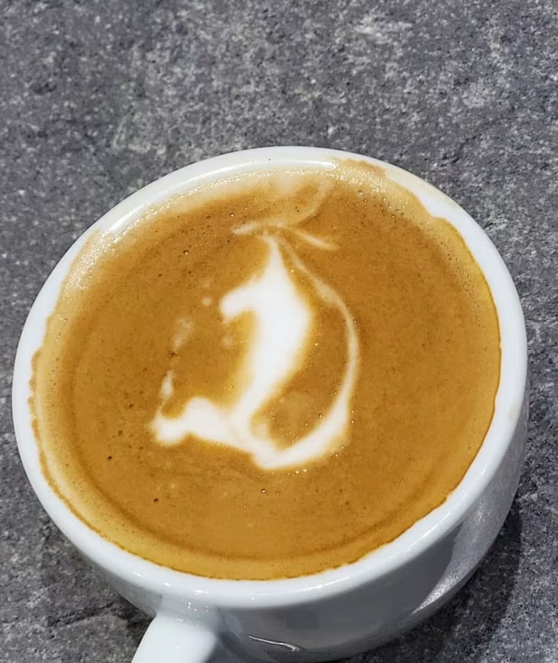 a cup of coffee with a picture of a horse on the top of it and a spoon next to it in Kelowna by Half Blind Bean Coffee