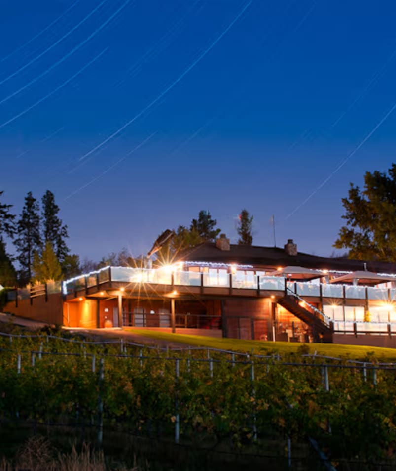 a large building with a lit up roof and a white tent in front of it at night with trees in the background