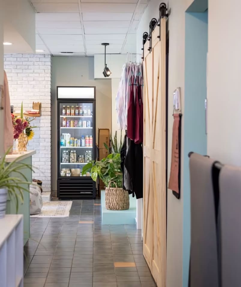 a long hallway with a bunch of towels hanging on the wall and a potted plant in the corner