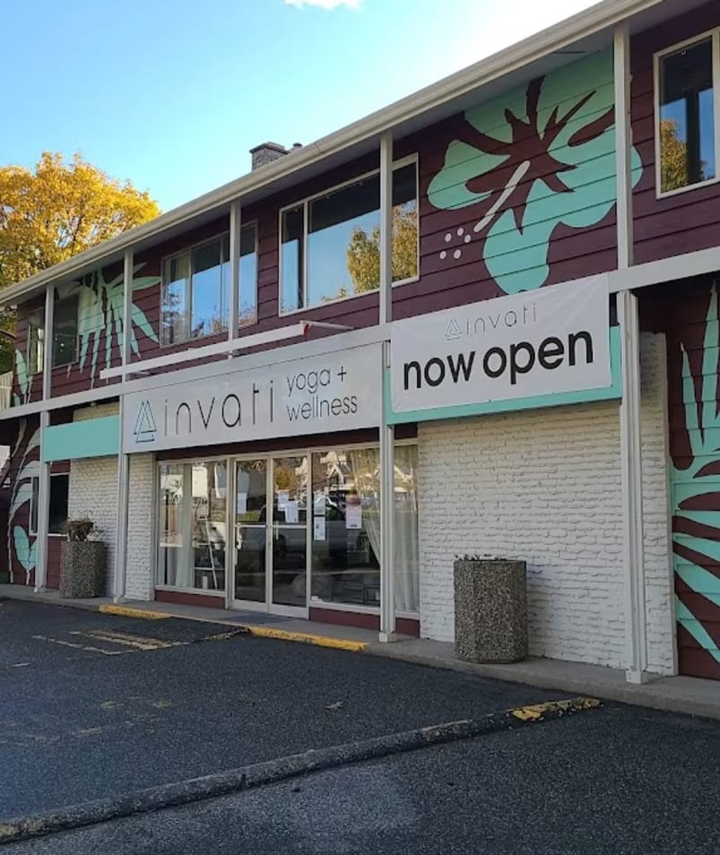 a building with a sign that says now open on the side of the building and a parking lot in front of it