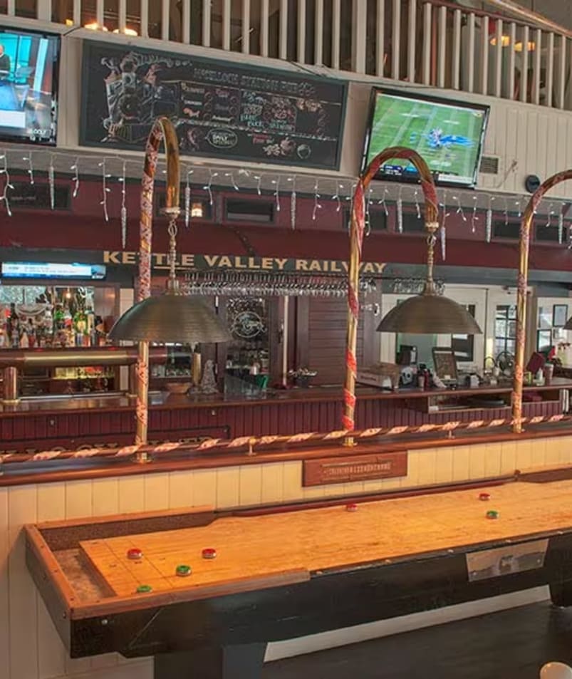 a room with a pool table and several televisions on the wall and a bar in the middle of the room