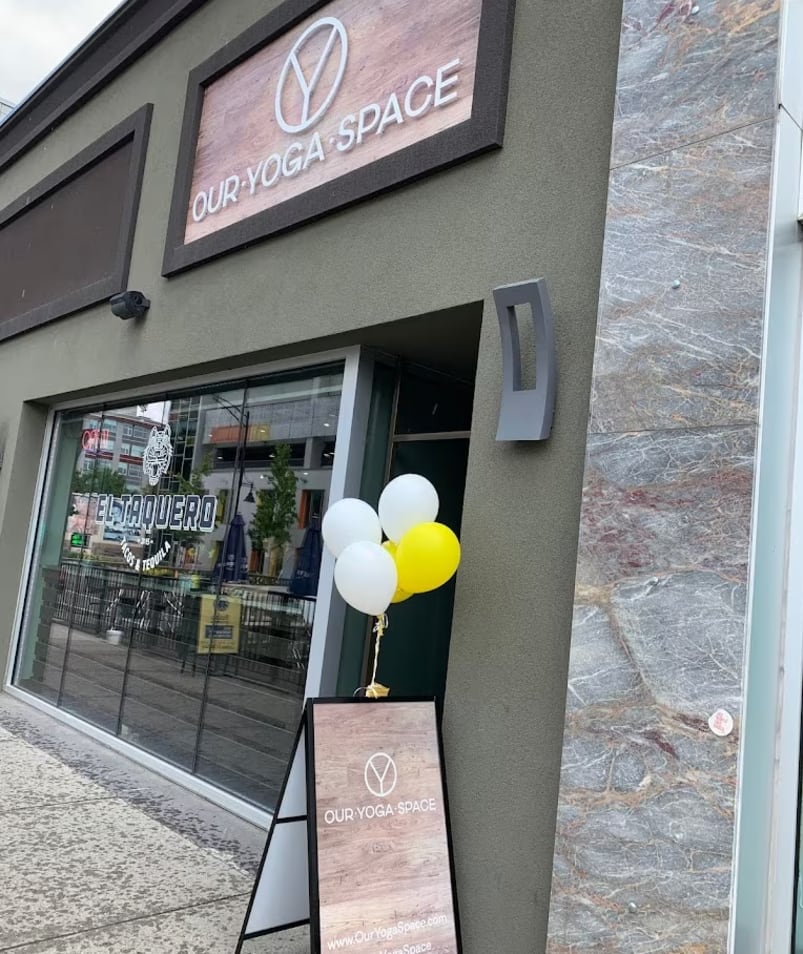 Exterior view of Our Yoga Space in Kelowna with a sign and balloons in front of the entrance.