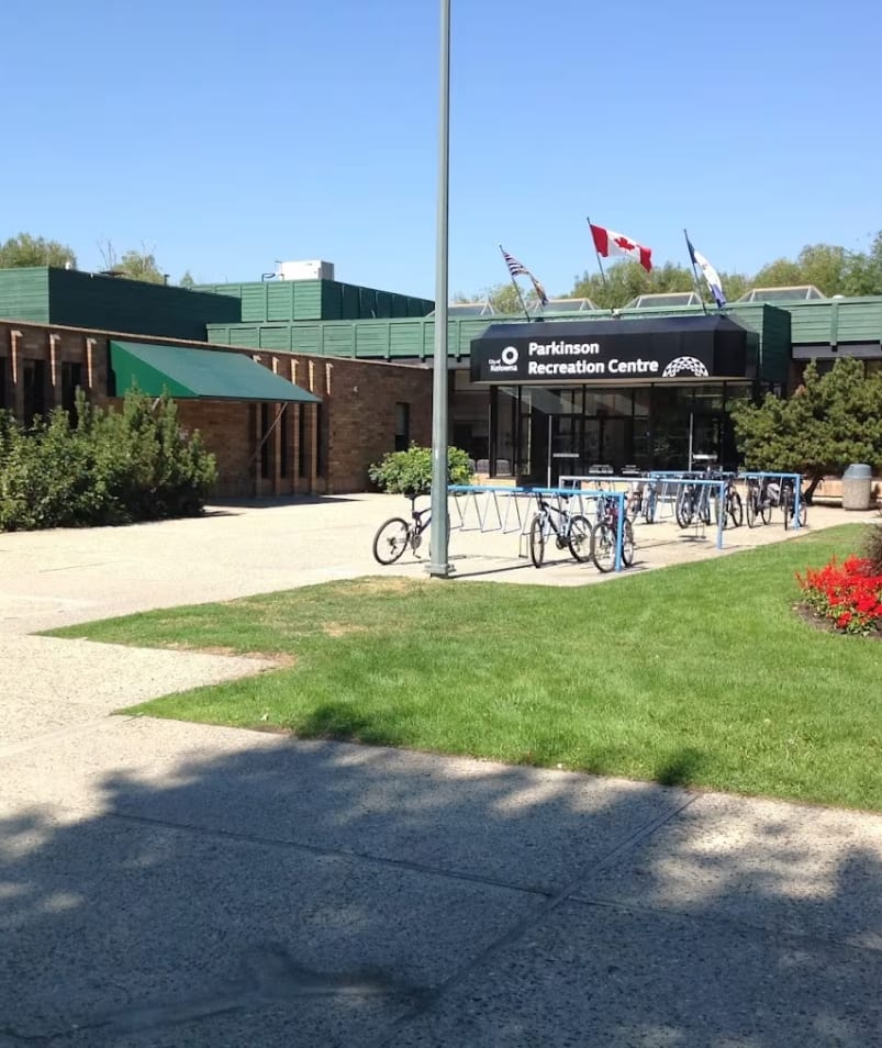 a bike parked in front of a building with a flag pole in the middle of the building and flowers in the front of the building.