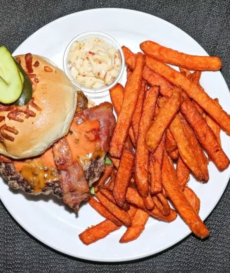 a white plate topped with a burger and french fries next to a side of macaroni and cheese