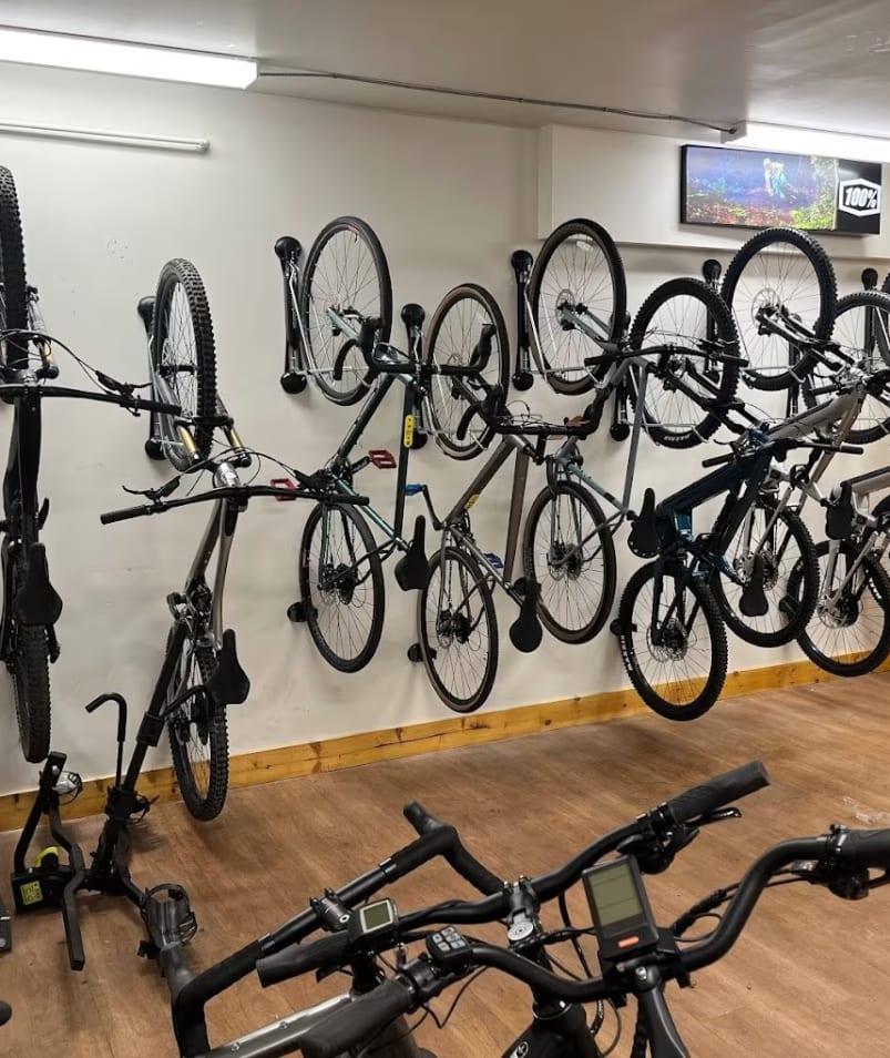 a room filled with lots of bikes and bicycles mounted to the wall next to a wall-mounted bike rack
