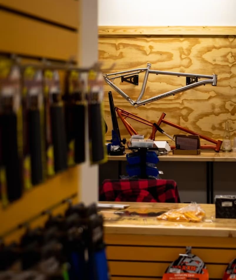 a bike shop with a lot of tools on the counter and a bike hanging on the wall behind it