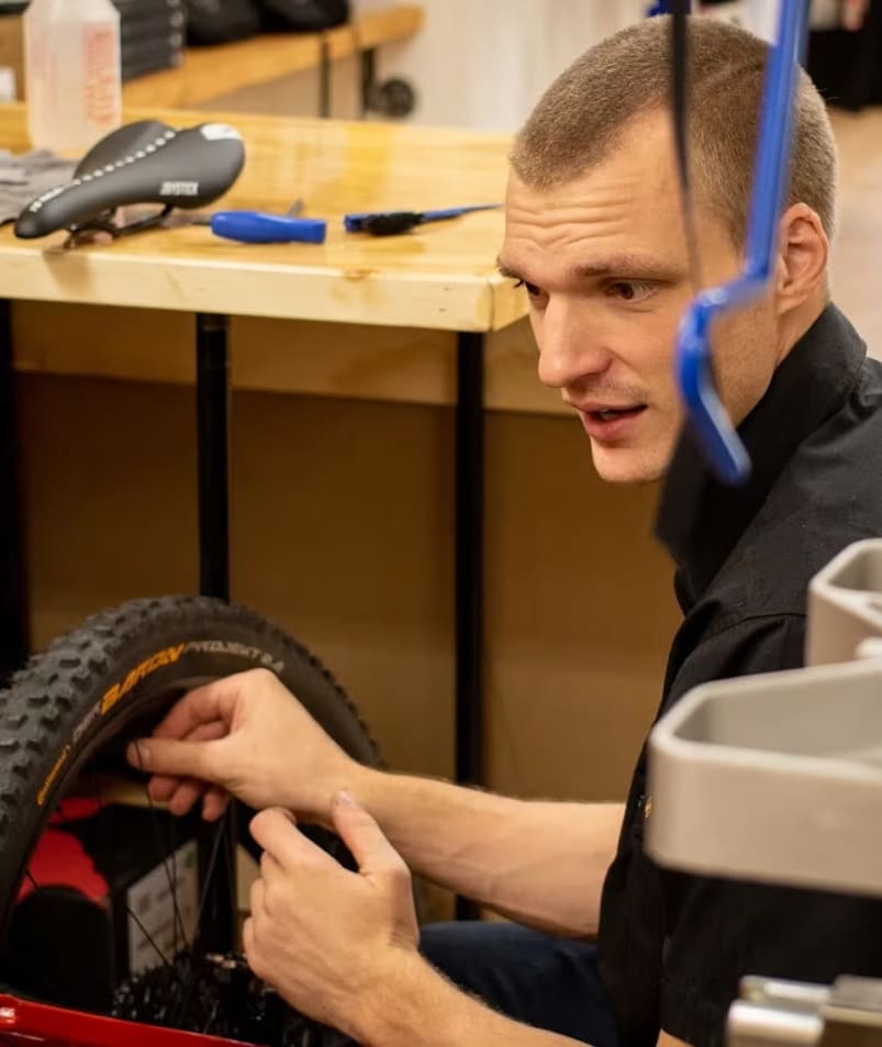 a man is working on a bicycle in a shop with tools on the table and on the wall behind him