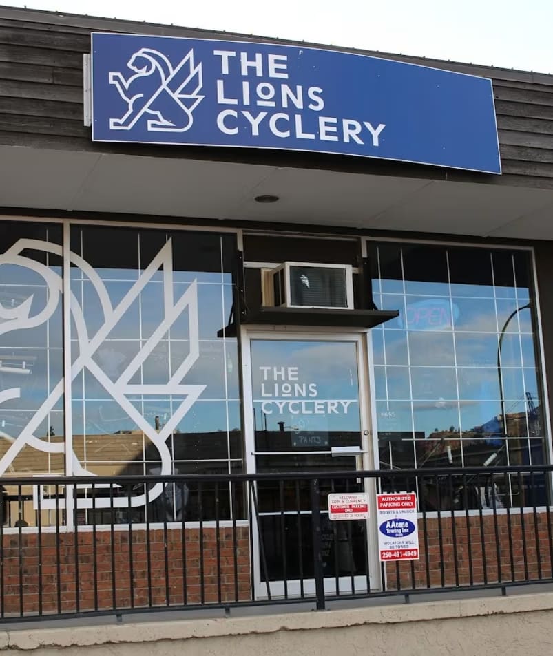 a building with a sign that says the lions cyclery on the front of it and a clock on the outside of the building