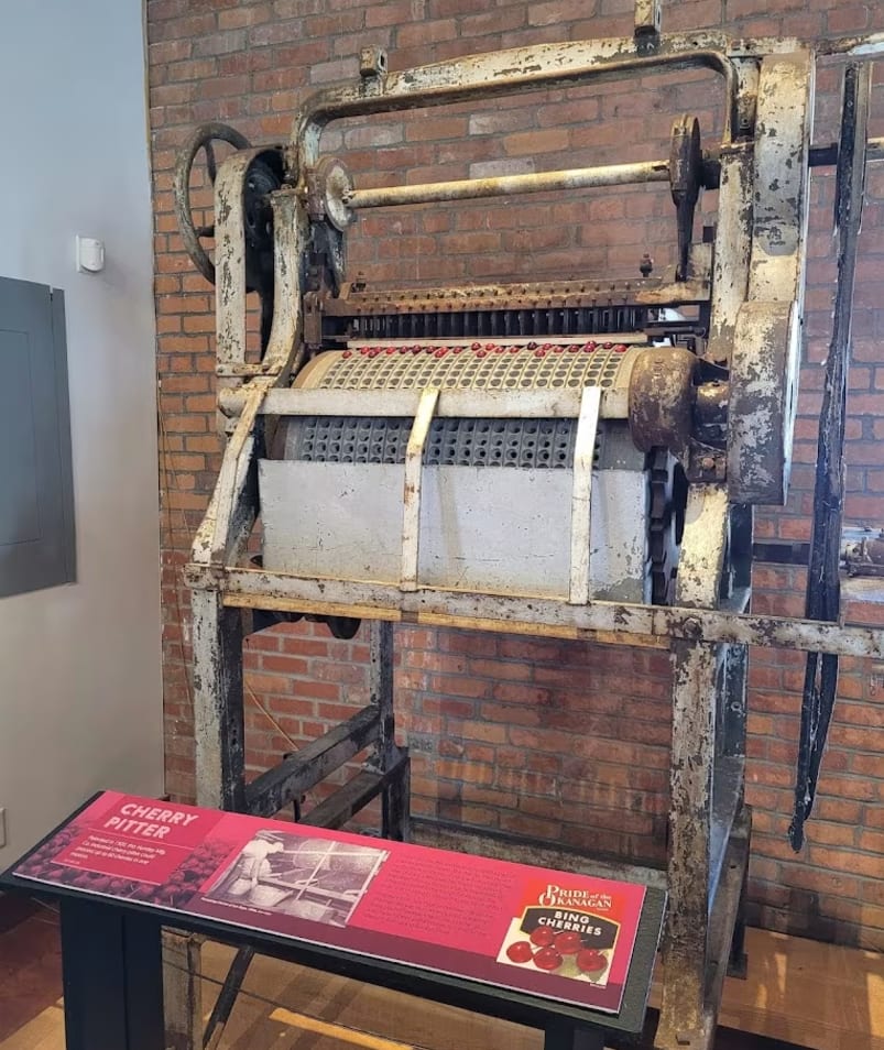 a large machine sitting on top of a wooden table next to a brick wall with a sign on it.