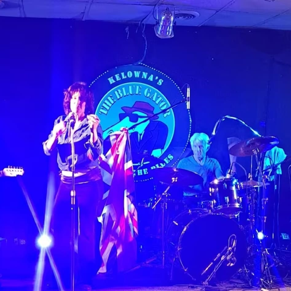 a group of people that are on a stage with a microphone and a guitar in front of a microphone stand at The Blue Gator Pub in Kelowna.