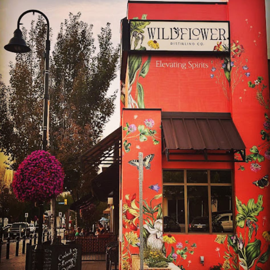 A vibrant red building with a floral mural and a sign reading "Wildflower Distilling Co." and "Elevating Spirits" in Penticton, BC.