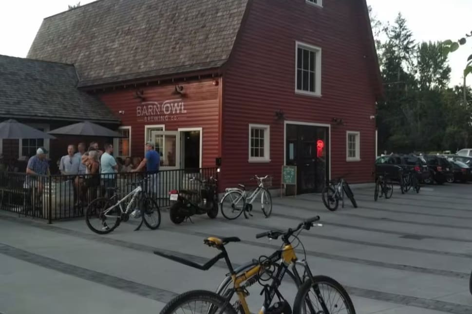 The exterior of the Barn Owl Brewing barn with many bicycles locked up out front.