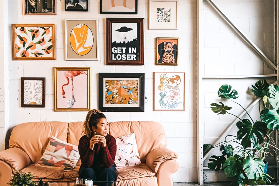 A woman sitting on a couch in front of a wall full of pictures and a coffee table in front of her at Bright Jenny Coffee Shop in Kelowna