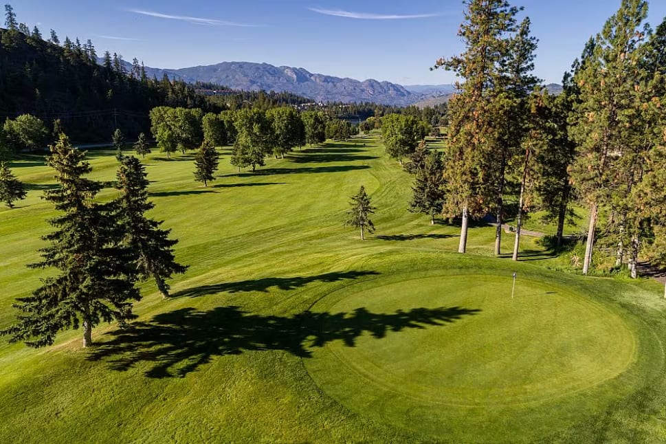 a view of a golf course with trees and a mountain in the background of the photo at Shannon Lake Golf Course, West Kelowna.