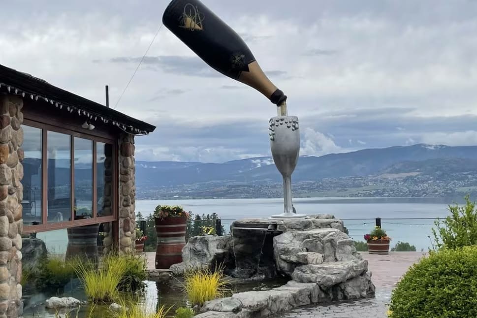 a large bottle of champagne being lifted into the air by a giant wine bottle in front of a house