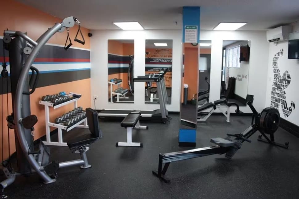 a gym with a row of exercise machines and a row of exercise machines in the corner of the room