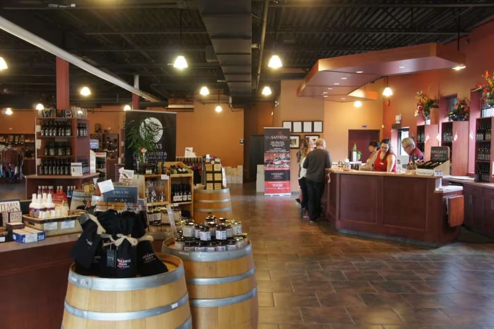 Interior view of the Volcanic Hills Estate Winery in West Kelowna with a tasting bar, wine displays, and customers.