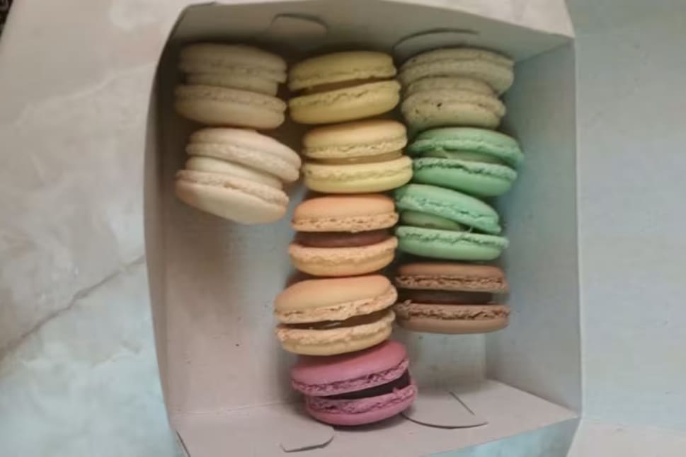 A white box filled with lots of different colored macarons.