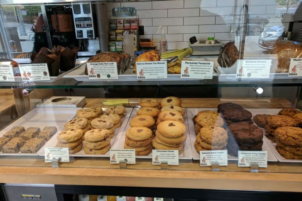 a display case filled with lots of different types of doughnuts and pastries in front of a store window.