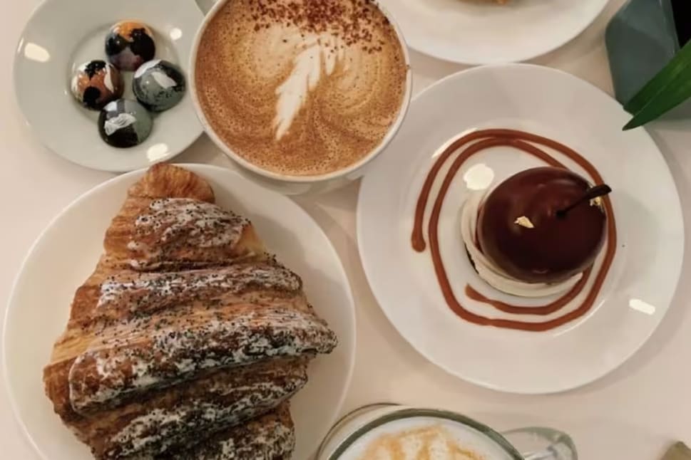 a white table topped with plates of food and a cup of coffee on top of a white table cloth