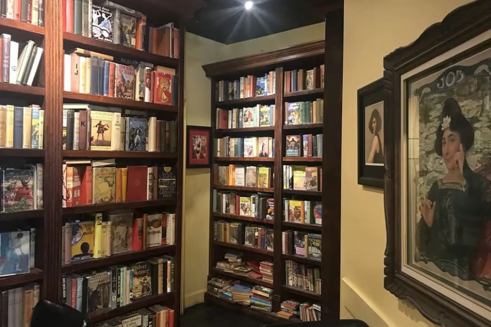 a room with a lot of books on the shelves and a chair in front of the bookshelf