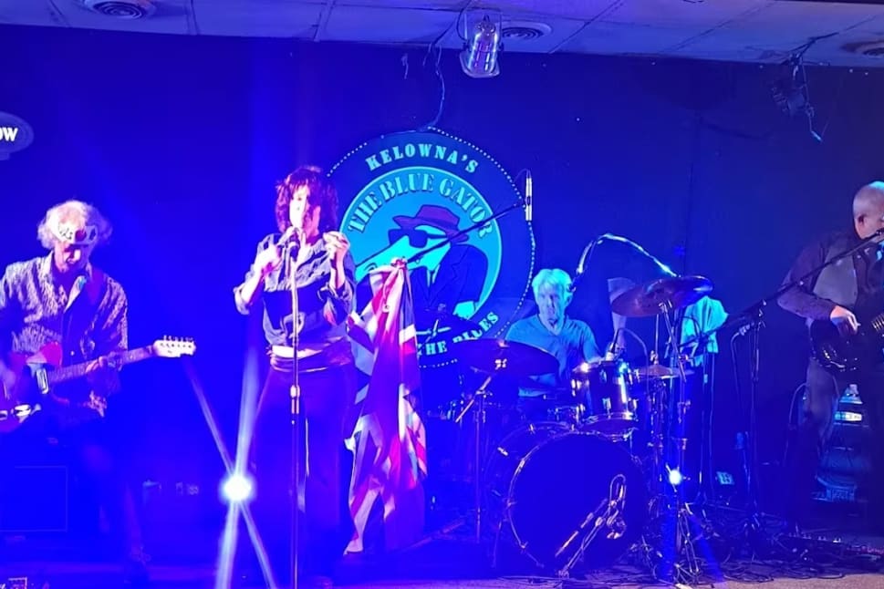 a group of people that are on a stage with a microphone and a guitar in front of a microphone stand at The Blue Gator Pub in Kelowna.