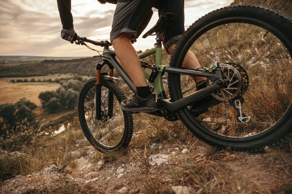 Person riding a mountain bike on a trail with a scenic view in the background.