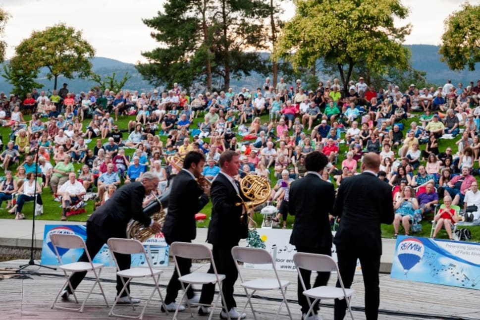 Outdoor concert at Park’s Alive! in Kelowna with a large audience and a group of musicians preparing to perform.
