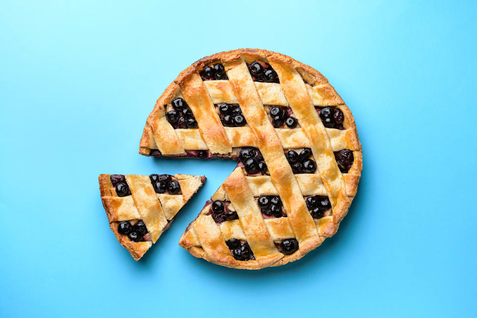 A blueberry lattice pie with a slice taking out on a bright blue background