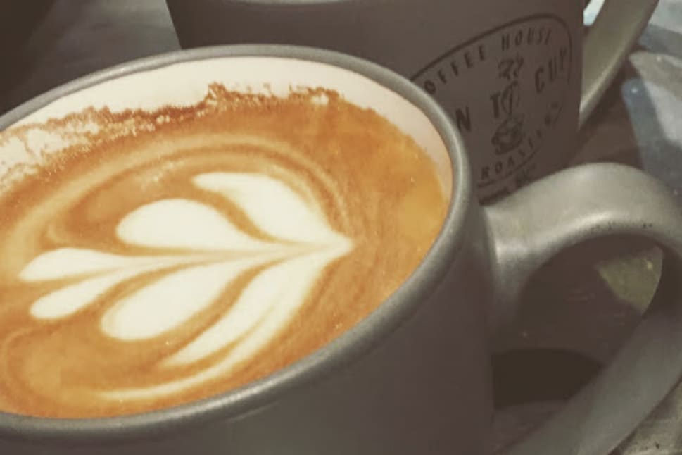 Two cups of latte with heart-shaped latte art served in grey mugs from Bean-To-Cup cafe in Vernon.