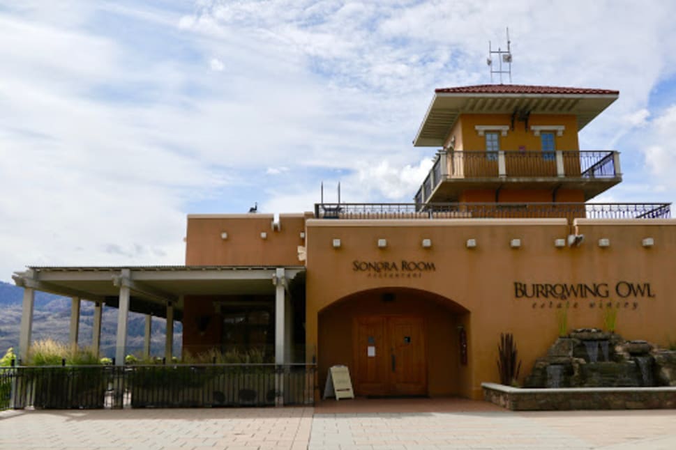 Exterior view of Burrowing Owl Estate Winery showing the main building with "Sonora Room restaurant" and "Burrowing Owl Estate Winery" signs.