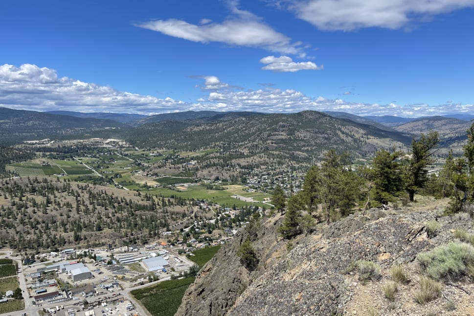 Scenic view of Summerland with mountains, a sprawling valley, and small town buildings under a partly cloudy blue sky.