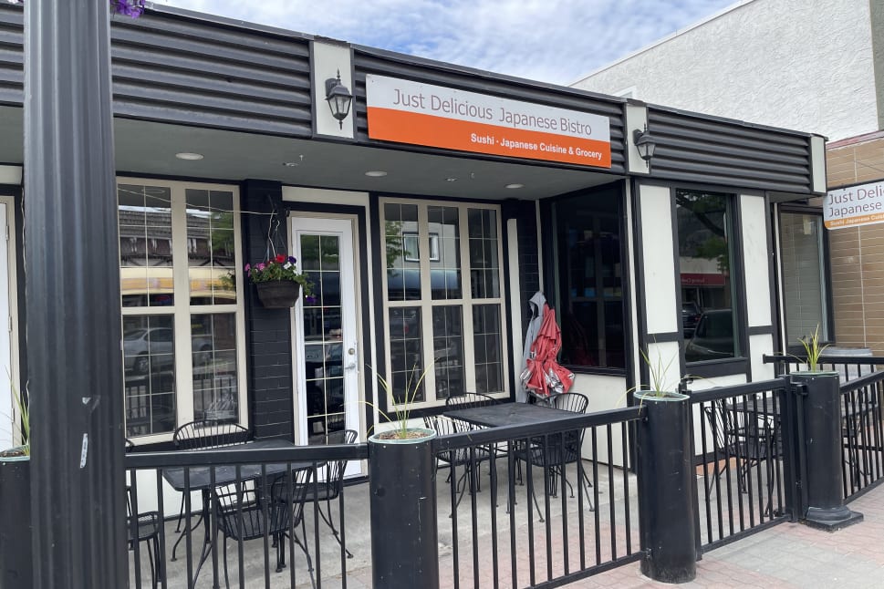 Outdoor seating area of Just Delicious Japanese Bistro with black chairs and tables, located in Summerland.