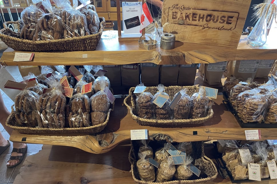 An assortment of baked goods in clear packaging on wooden shelves, displayed at the Bakehouse in Summerland.