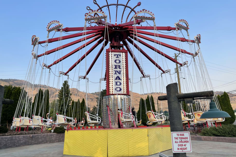 A view of the Tornado amusement ride with empty seats and mountains in the background at an amusement park in Osoyoos.