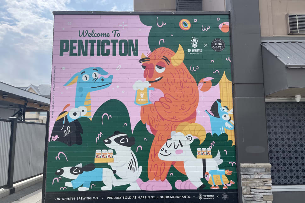 A colorful mural featuring whimsical animals and a friendly monster holding beers welcomes visitors to Penticton.